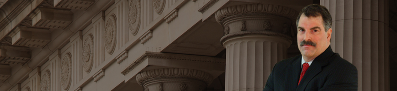 David C. Ricci standing confidently with his arms crossed in front of a courthouse with prominent columns.